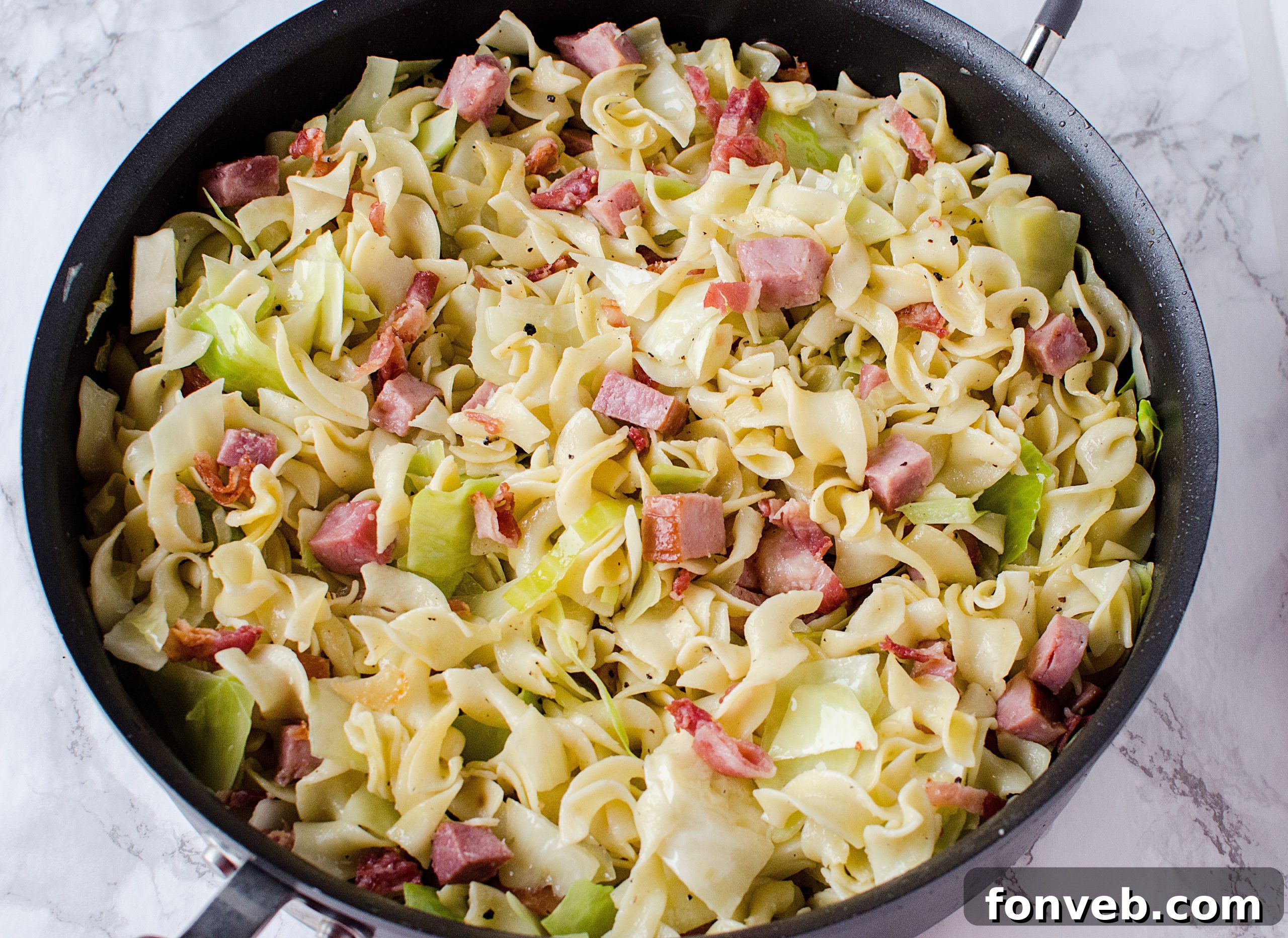 Serving Haluski from the large skillet directly onto a plate, showcasing its family-style appeal.