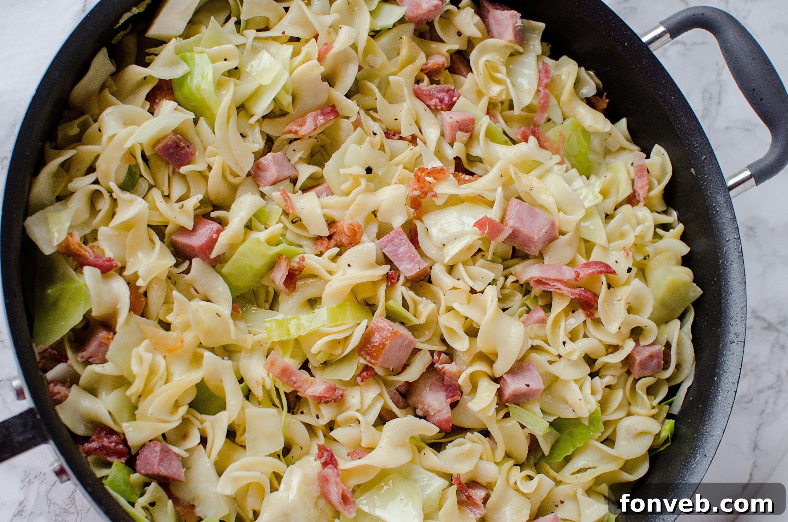 Cubed ham browning in a skillet with butter, forming the base of the Haluski's rich flavor.