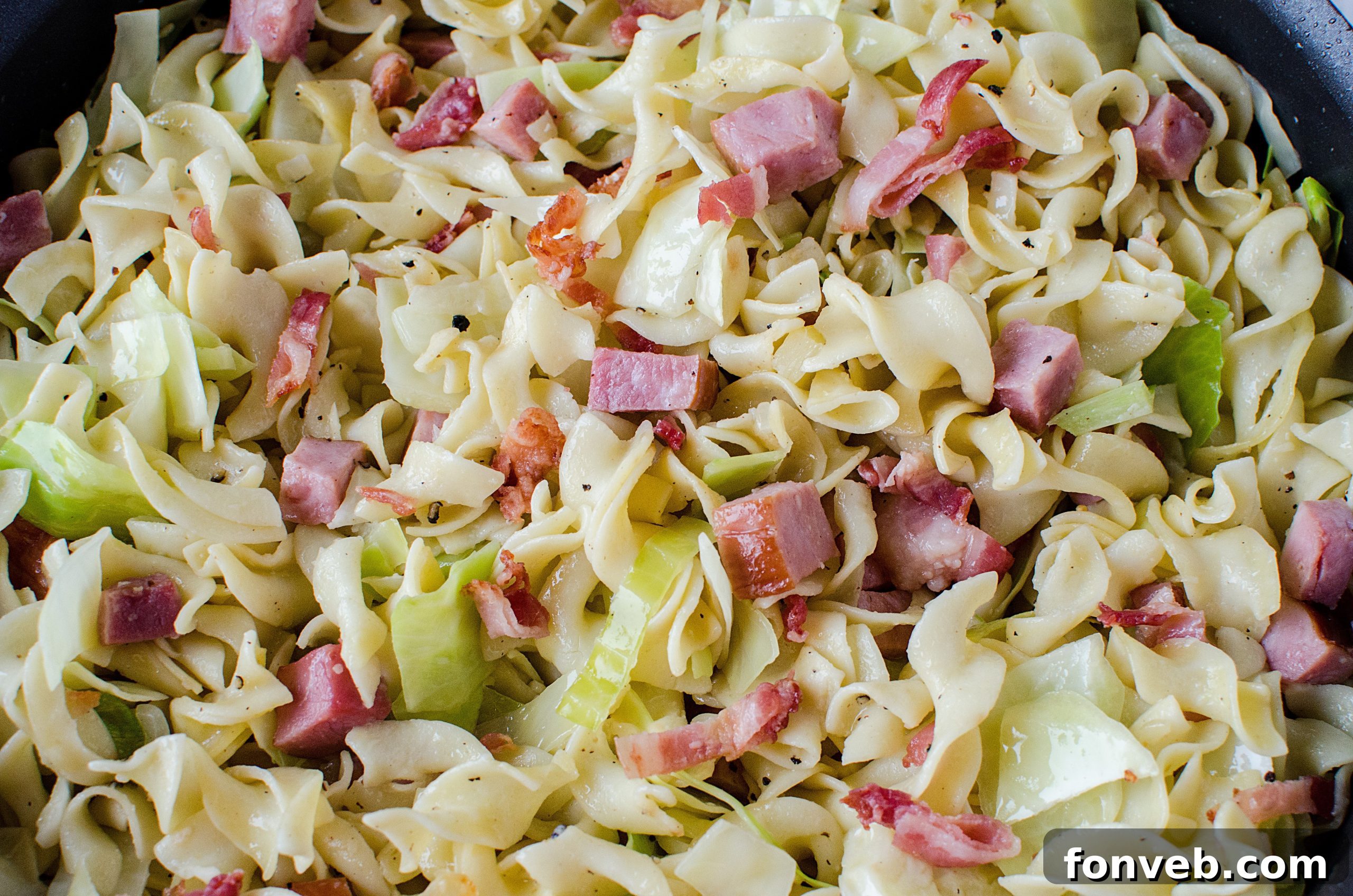 Golden-brown ham cubes mixed with sautéed onions and garlic in a large pan.