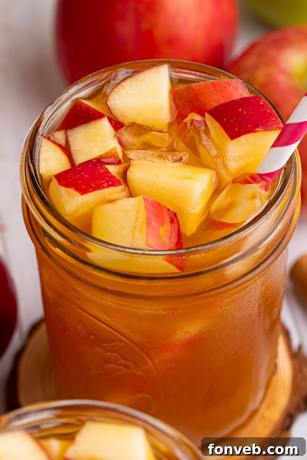 tea cider in a glass with diced apples and ice in the glass