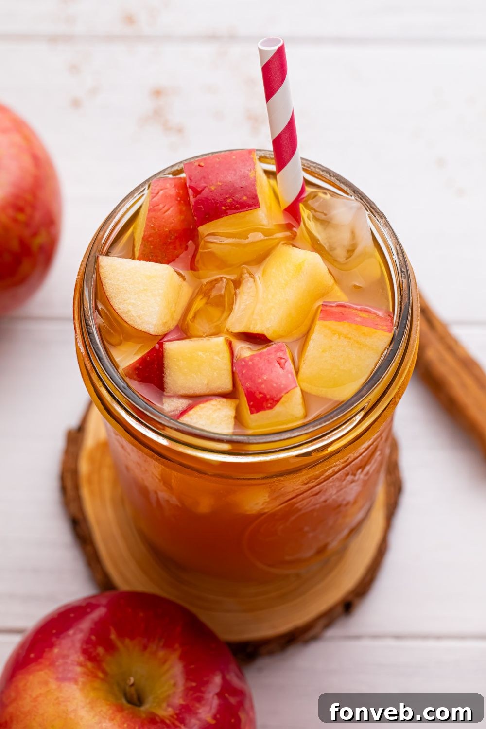 close up of mason jar with apple cider tea in it and a red and white straw sticking in it 