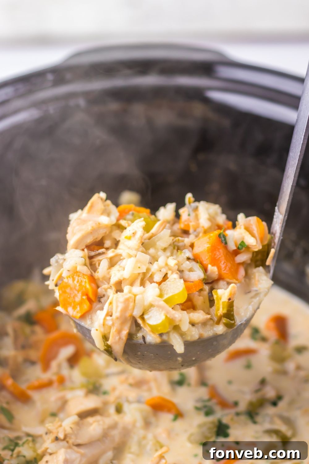 Slow Cooker Turkey & Rice Soup on table with a metal spoon scooping the soup out of the slow cooker 