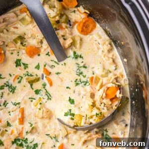 Slow Cooker Turkey And Rice Soup in a slow cooker with a large ladle in slow cooker