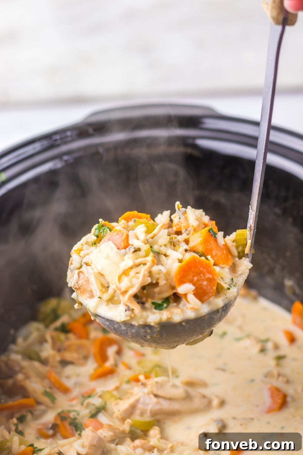 Slow Cooker with Turkey And Rice Soup with a ladle of soup being lifted out of the slow cooker