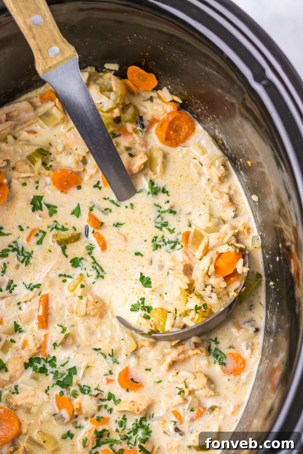look of slow cooker that is full of a creamy turkey and rice soup that is studded with colorful vegetables