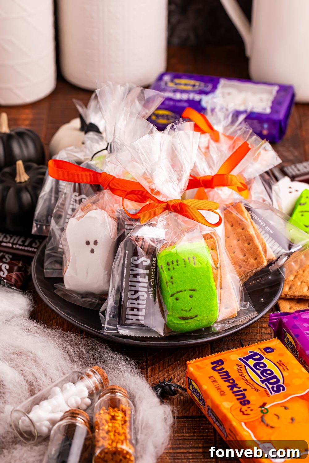 Spooky S'mores Kits 11 Halloween Smores Gift Bags on a plate with fake spider web and bags of marshmallows on table around to show ingredients in bags