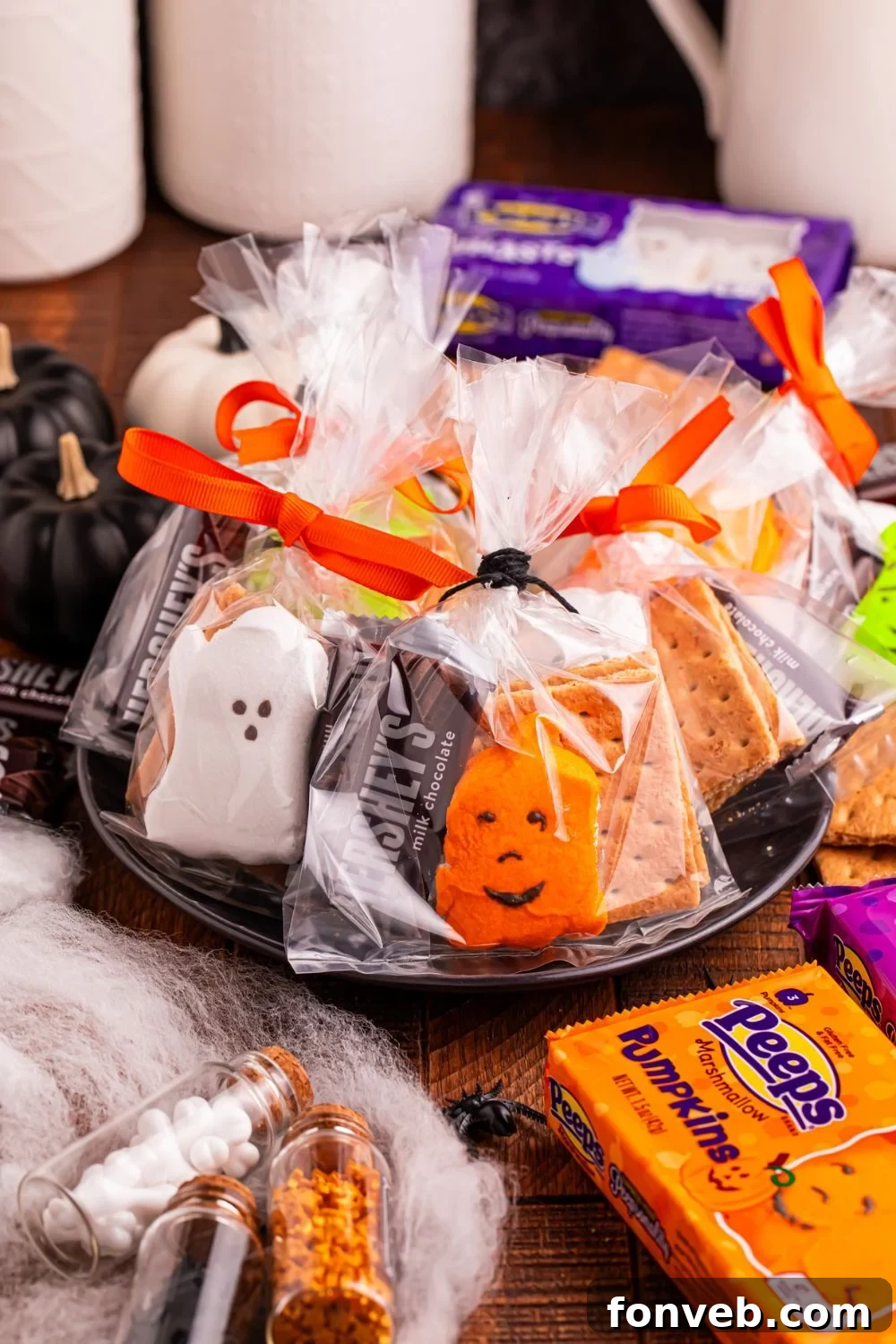 Spooky S'mores Kits 13 Halloween Smores Gift Bags on table with candy and other items around it to show items in each of the treat bags