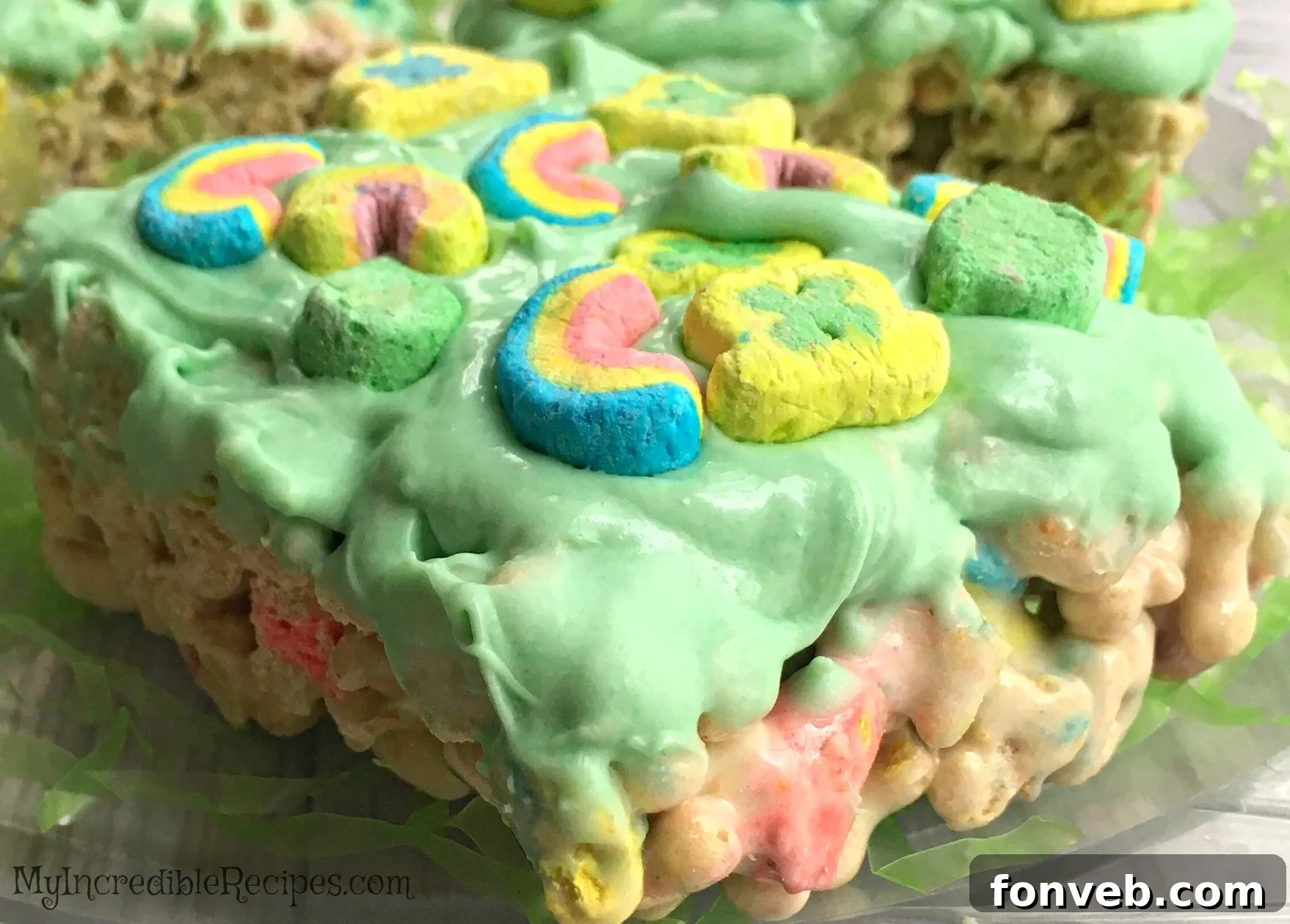 A plate of freshly made Lucky Charms Cereal Bars, some dipped in green chocolate and topped with extra marshmallows.
