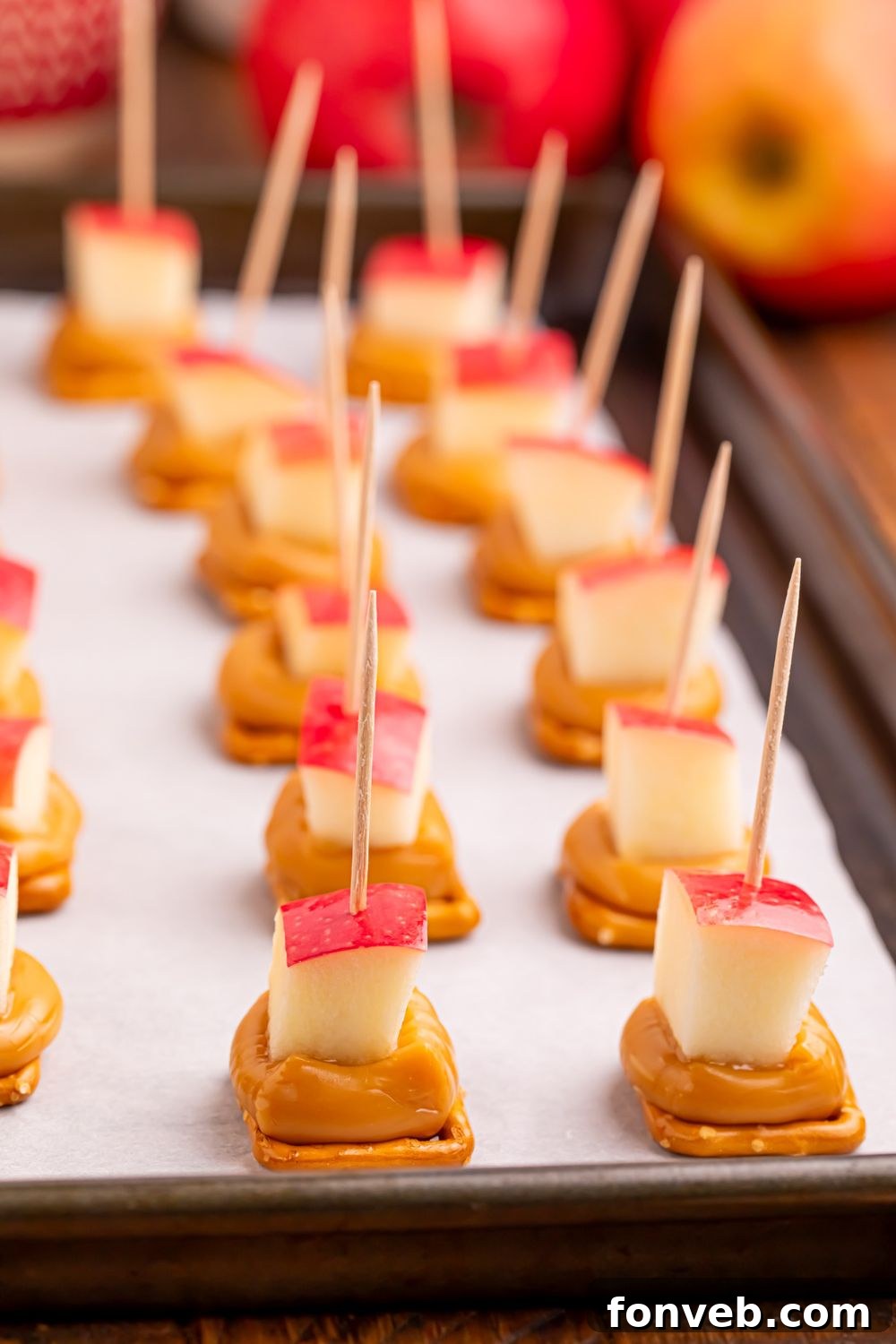 caramel apple bites with pretzels spread out on a cookie tray on table