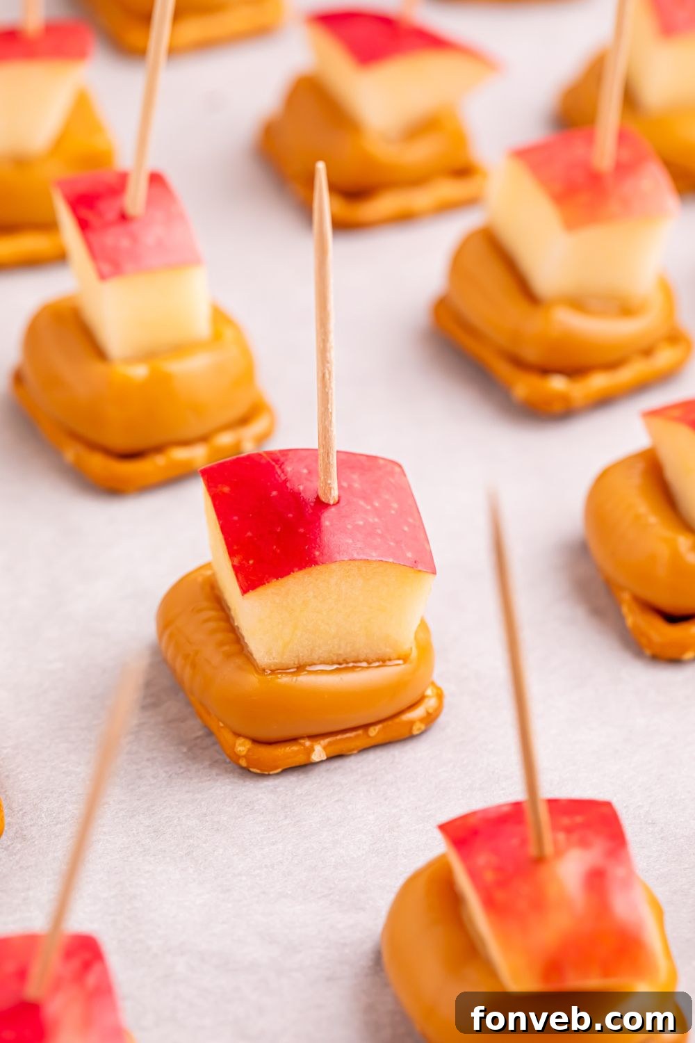 caramel apple bites on toothpicks sitting on a cookie tray 