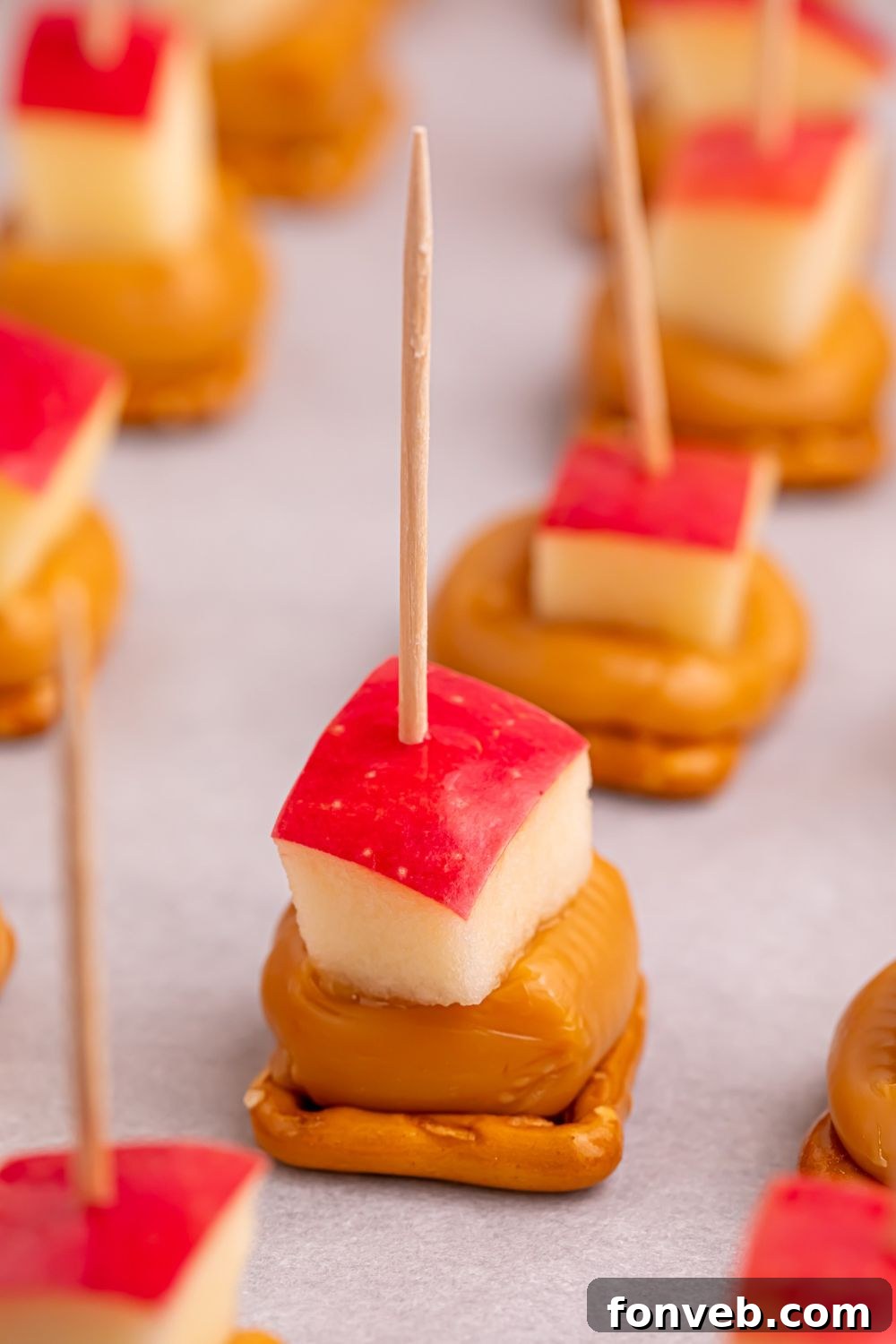 pretzel caramel bites with apples on top and toothpicks sitting on tray