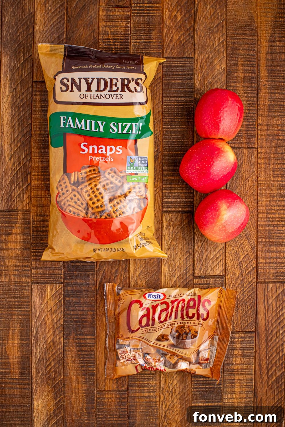 Caramel Apple Pretzel Bite ingredients on wooden table: bag of pretzels, apple, caramels in bag
