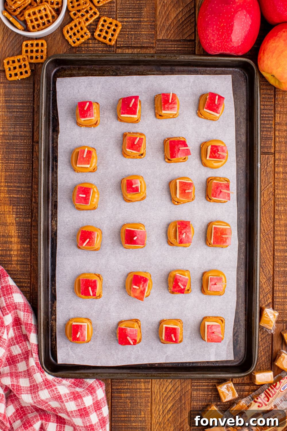 caramel apple bites on a baking sheet that are assembled and topped with pretzels 