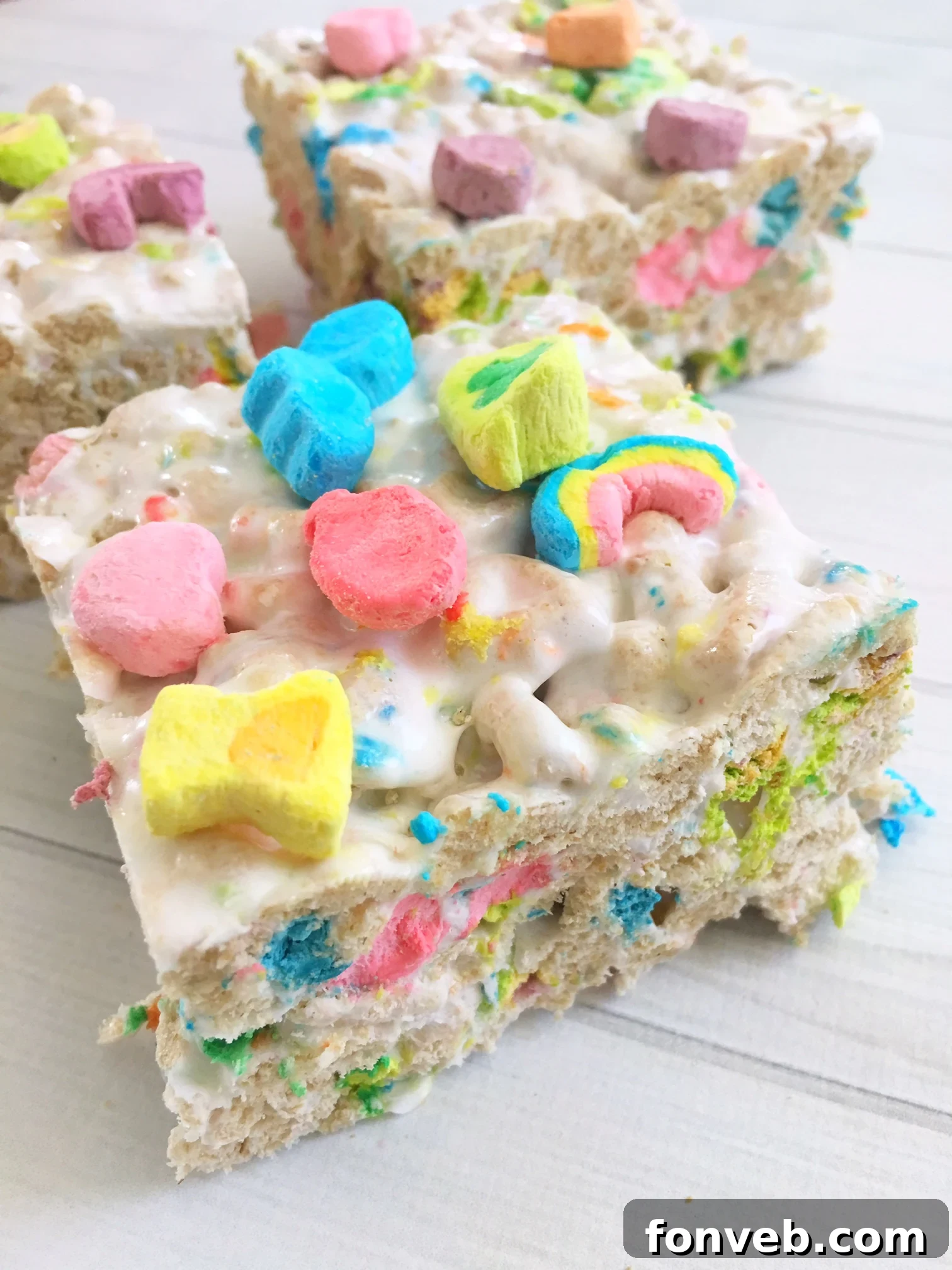 A stack of three thick, bakery-style Lucky Charms Krispy Treats, showing their impressive height and delicious layers.
