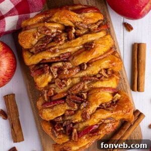 Apple Pie Pull Apart Bread on a cutting board on table with cinnamon sticks and apples around the serving tray