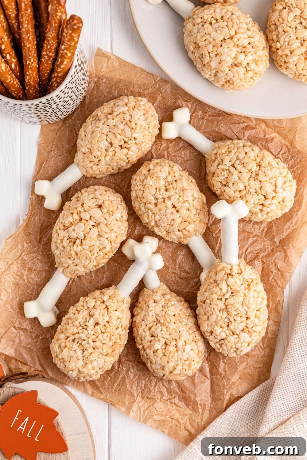 Festive Rice Krispie Drumsticks 2 A festive spread featuring Rice Krispie Treat Turkey Legs, surrounded by pretzel rods and other ingredients in bowls, creating a vibrant Thanksgiving table setting.