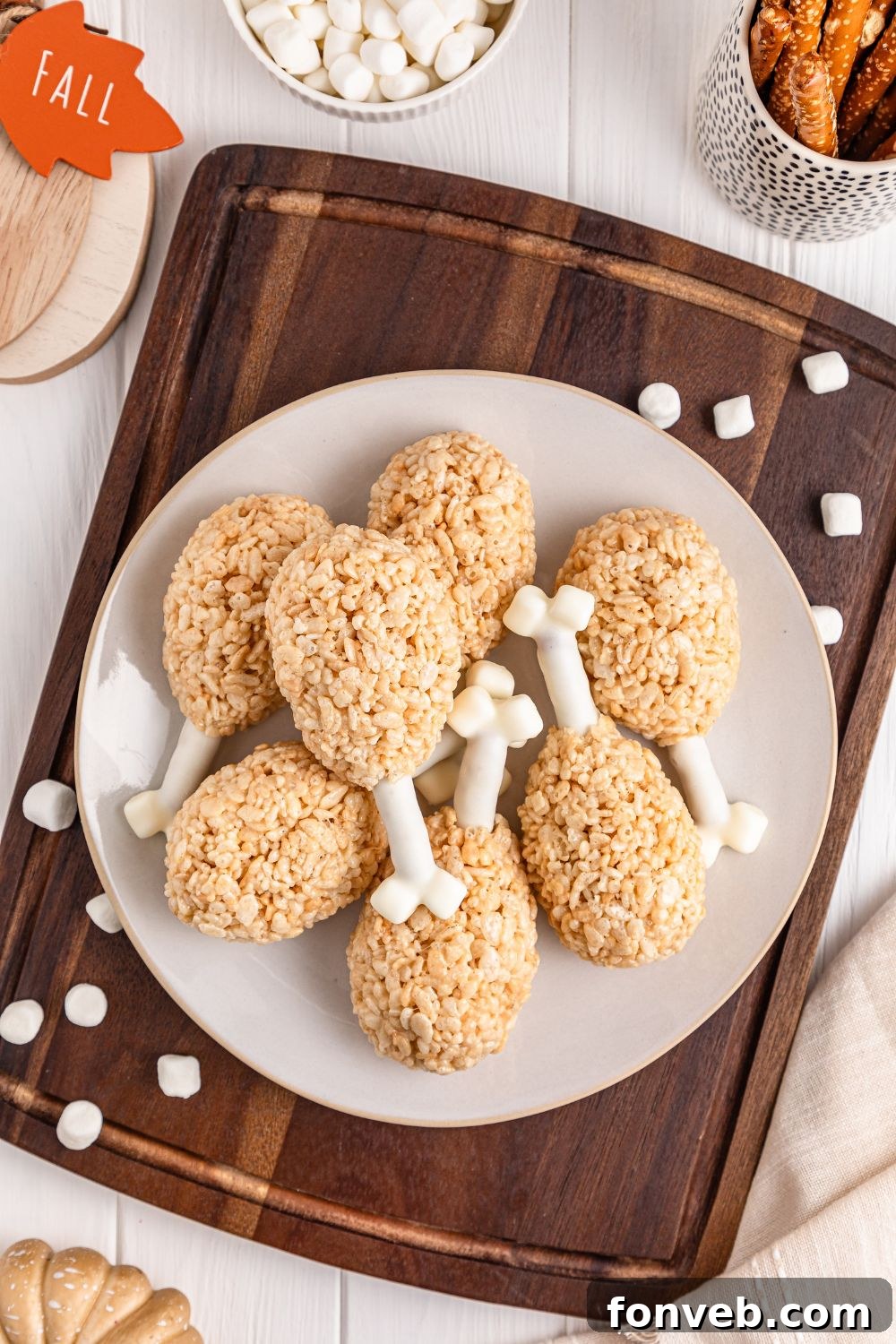 Festive Rice Krispie Drumsticks 14 Rice Krispie Treat Turkey Legs artfully presented on a platter on a table, surrounded by festive holiday decorations, enhancing their holiday charm.