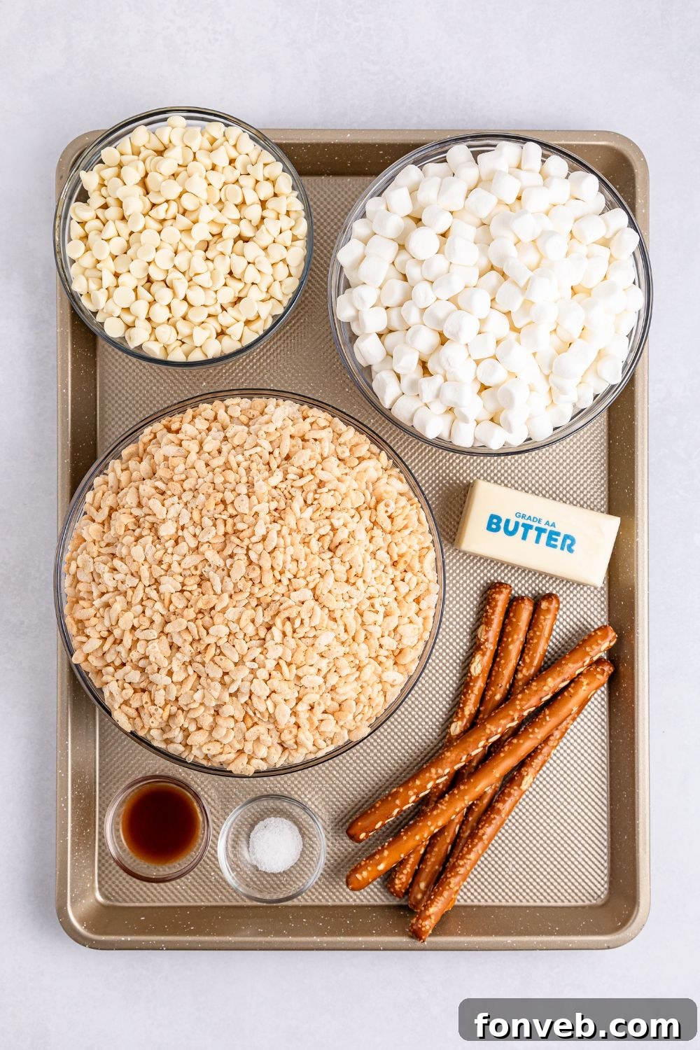 Festive Rice Krispie Drumsticks 5 A neatly arranged table displaying all the essential ingredients for Rice Krispie Treat Turkey Legs: a stick of butter, pretzel rods, Rice Krispies cereal, marshmallows, white chocolate, and other components in various bowls.