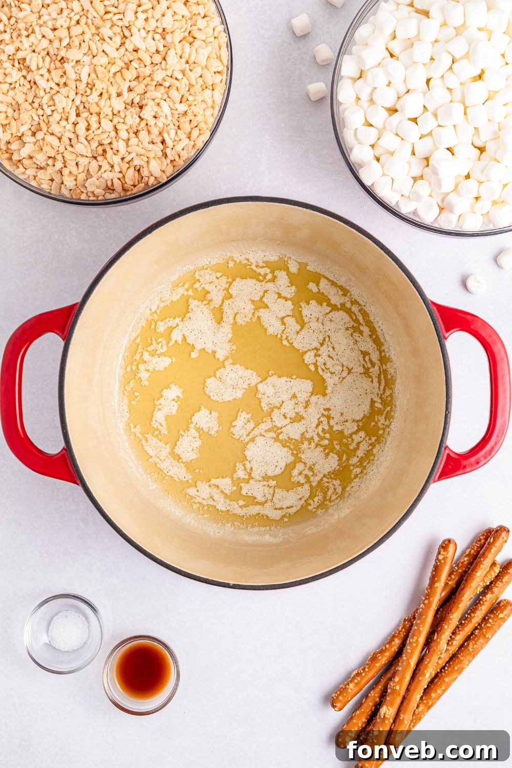 Festive Rice Krispie Drumsticks 8 Melted butter simmering in a pot, surrounded by cereal, marshmallows, and other ingredients on a table, signifying the start of the treat-making process.