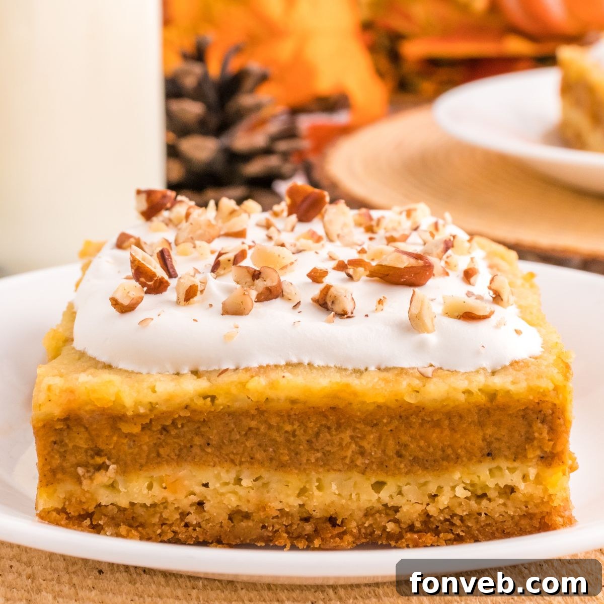 Harvest Pumpkin Pie Delight 2 A slice of Pumpkin Pie Cake on a plate, garnished with a dollop of whipped cream and a sprinkle of nuts, invitingly presented.