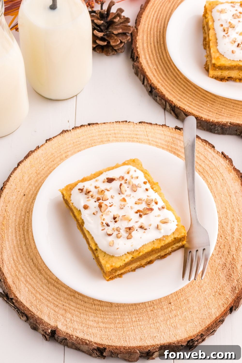 Harvest Pumpkin Pie Delight 14 A beautifully layered slice of pumpkin cake on a white plate, accompanied by two glasses of milk on the side, creating a cozy and inviting scene.