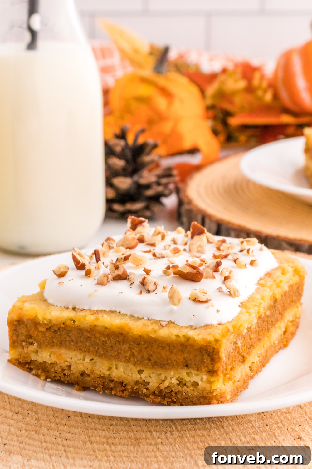 Harvest Pumpkin Pie Delight 3 A perfect slice of Pumpkin Pie Cake resting on a white plate, with a tall glass of milk positioned elegantly to its side, evoking a sense of comfort and indulgence.