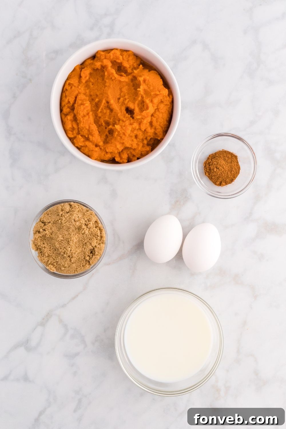 Harvest Pumpkin Pie Delight 4 Various ingredients for Pumpkin Pie Cake laid out on a wooden table, including a bowl of pumpkin puree, brown sugar, eggs, and a container of pumpkin pie spice.