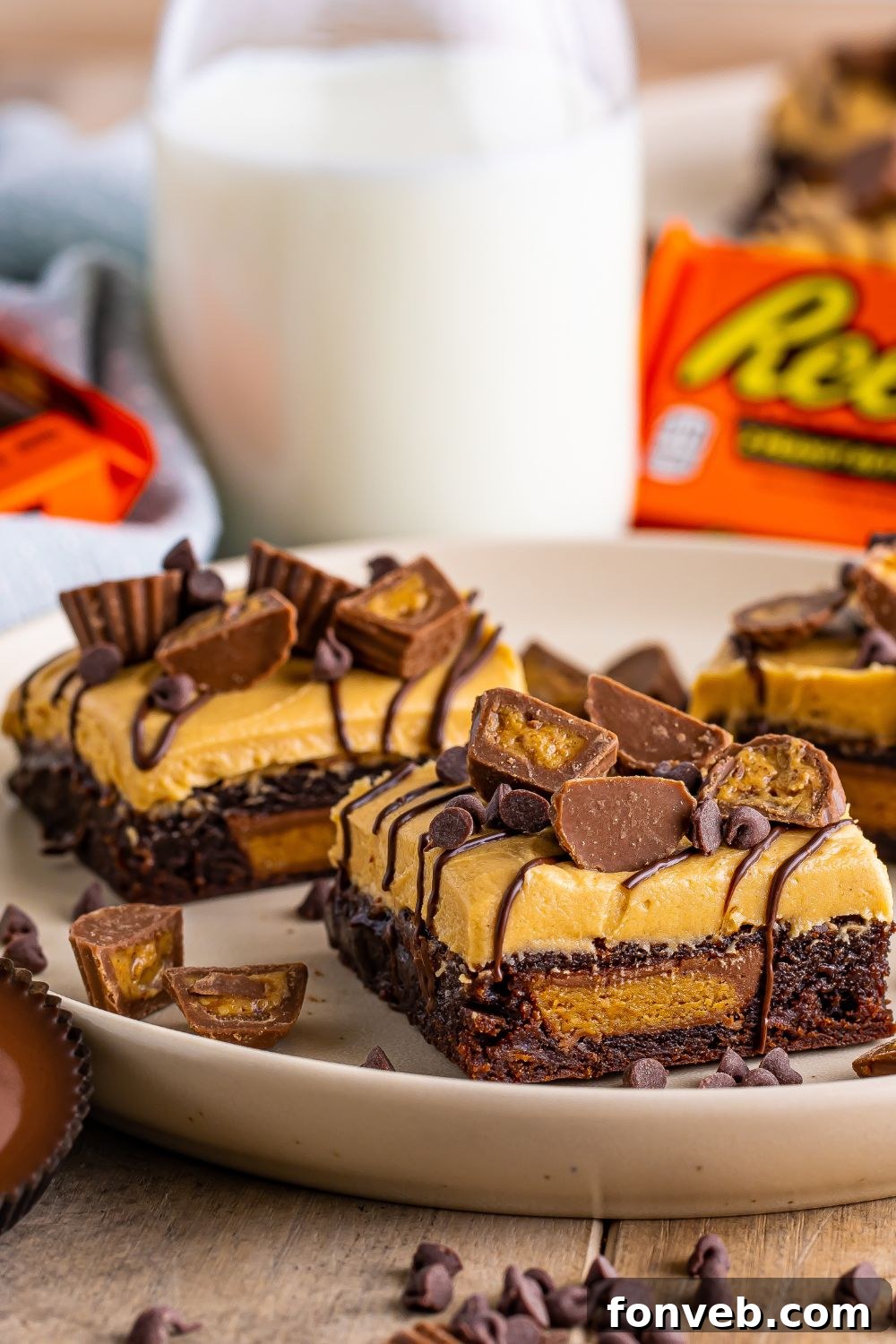A close-up view of brownies expertly sliced into squares, resting on a table, with a milk jug and scattered Reese's candies adding to the delightful presentation