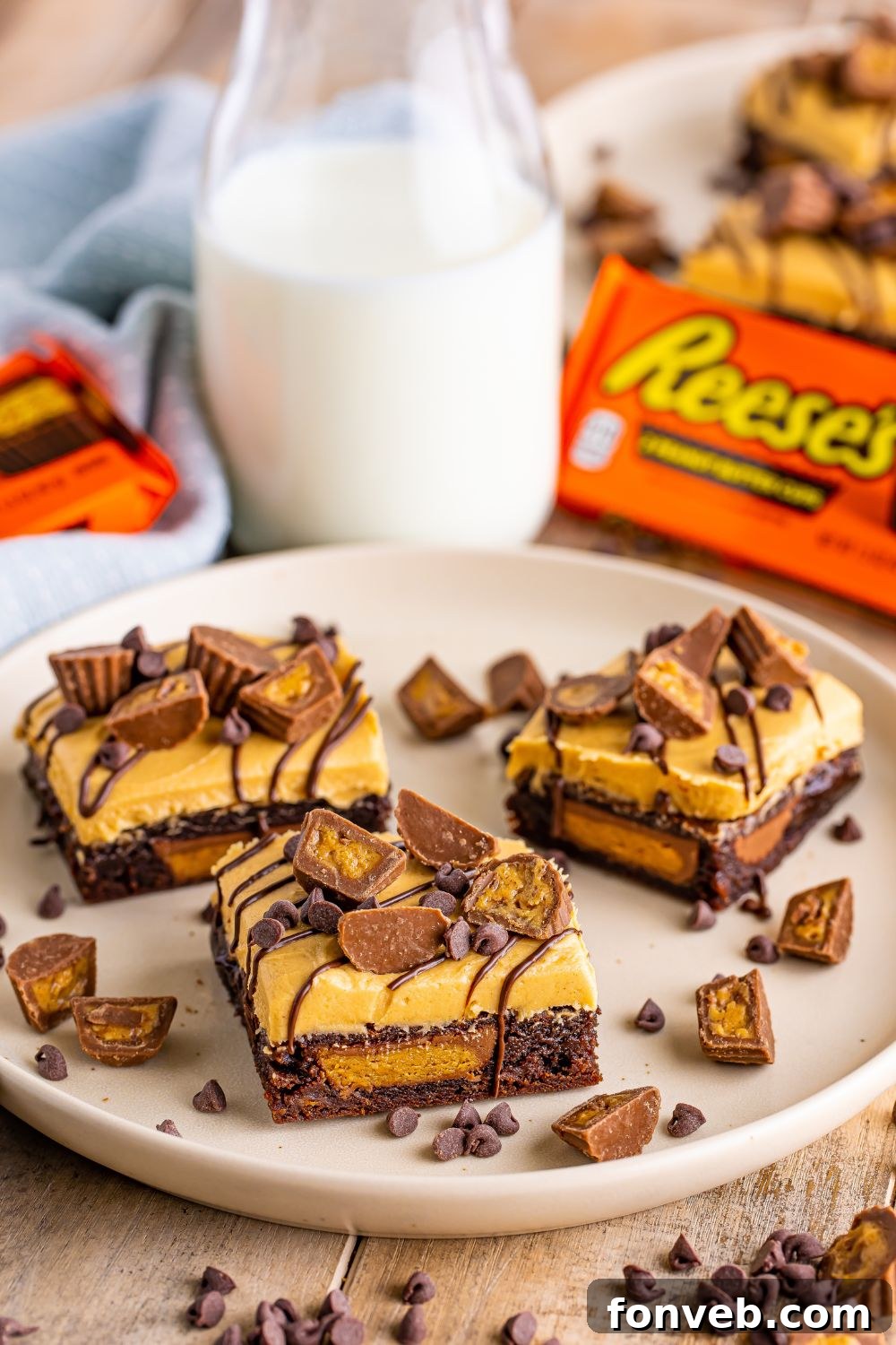 Reese's Stuffed Brownies on a plate, with a jug of milk and a Reese's candy package blurred in the background, setting a sweet scene