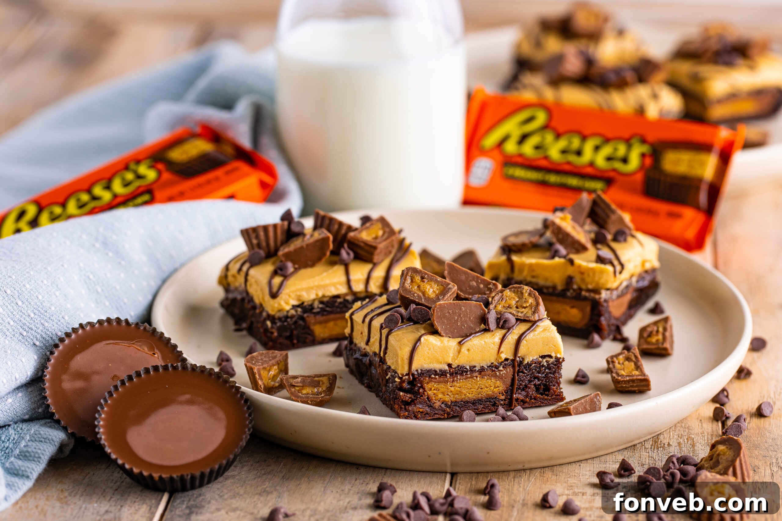 Reese's Stuffed Brownies arranged on a plate with a jug of milk and a Reese's package visible in the soft-focus background
