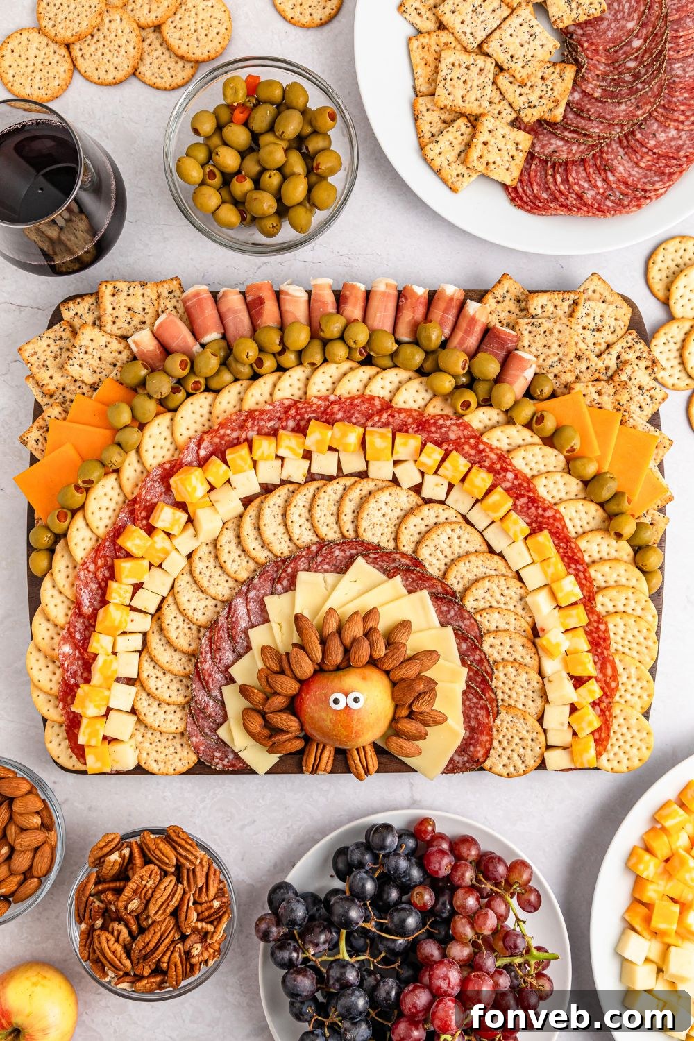 Turkish Bites Board 16 Thanksgiving Turkey Cheese Board on table with bowls of grapes, nuts, platters of meat and cheese surrounding the tray