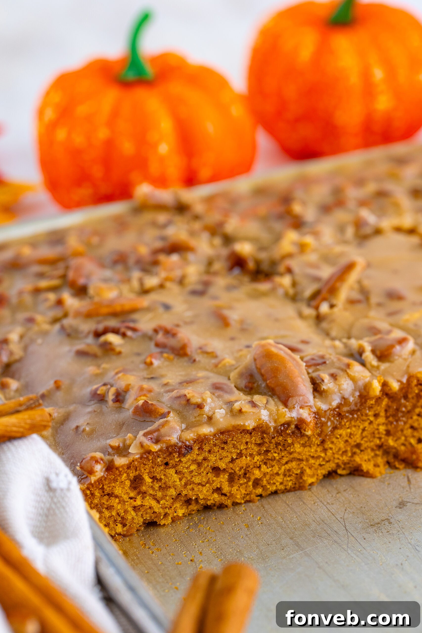 A large sheet pan of Pumpkin Snack Cake with Praline Icing, with several perfect slices already removed, showing the golden cake and rich topping.