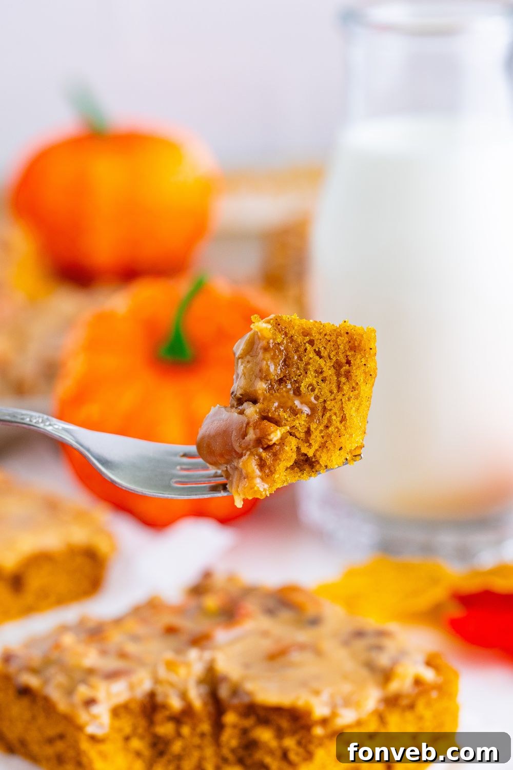 A delectable slice of pecan praline cake on a white plate, with a fork holding a bite raised above, ready to be savored.