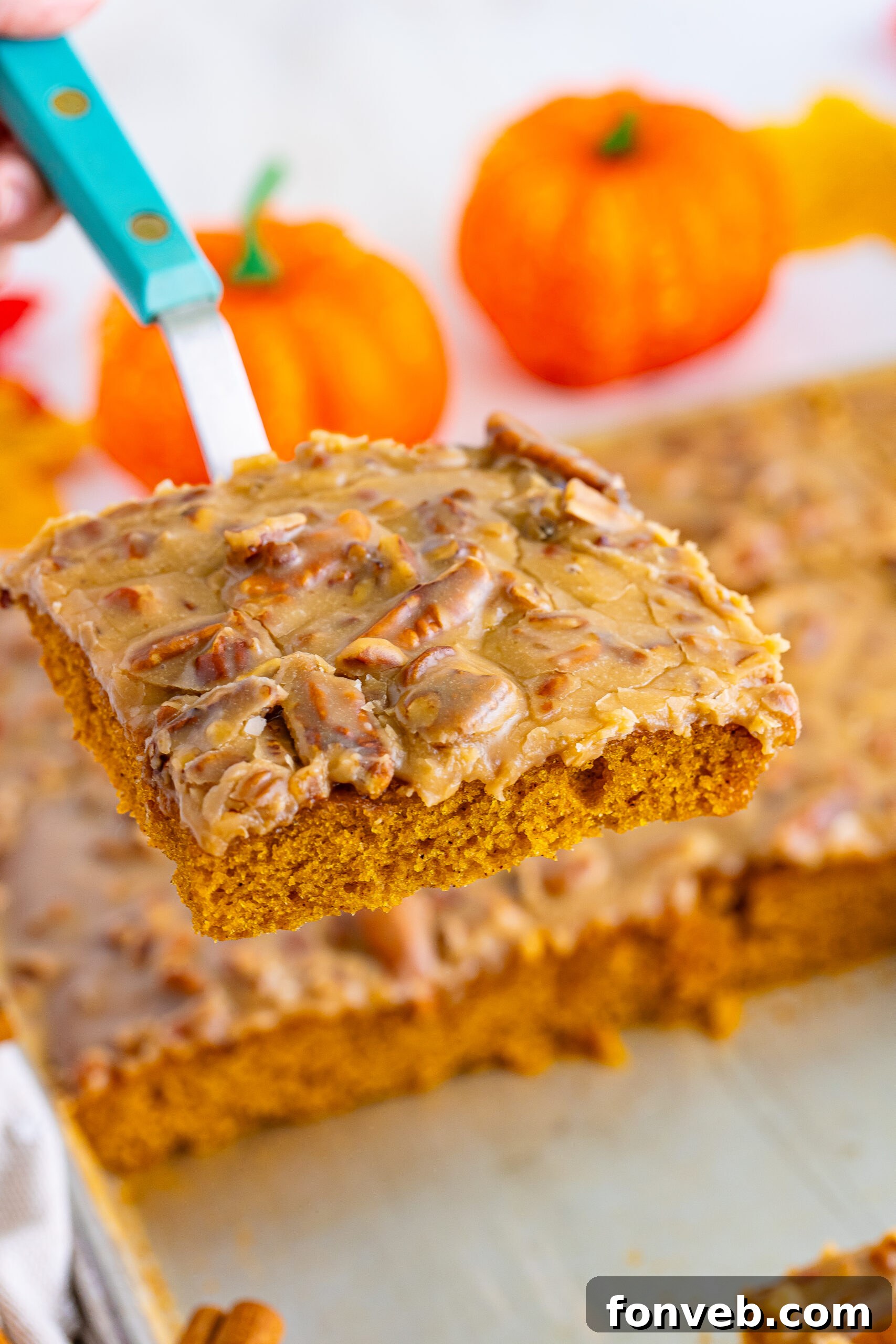 A spatula gently lifting a generous slice of Pumpkin Snack Cake with Praline Icing from the pan, ready to be served and enjoyed.
