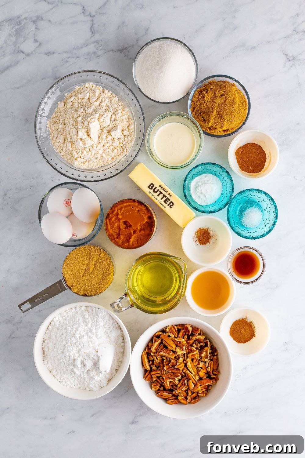 All the individual ingredients for the Pumpkin Snack Cake with Praline Icing laid out neatly in separate bowls on a table, ready for baking.