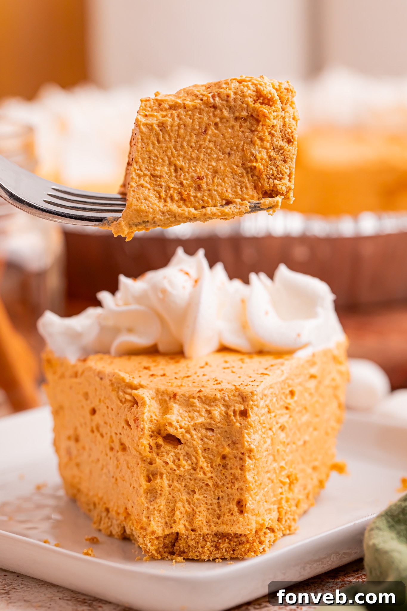 Marshmallow Pumpkin Pie slice on plate with a fork with a bite on it above plate 