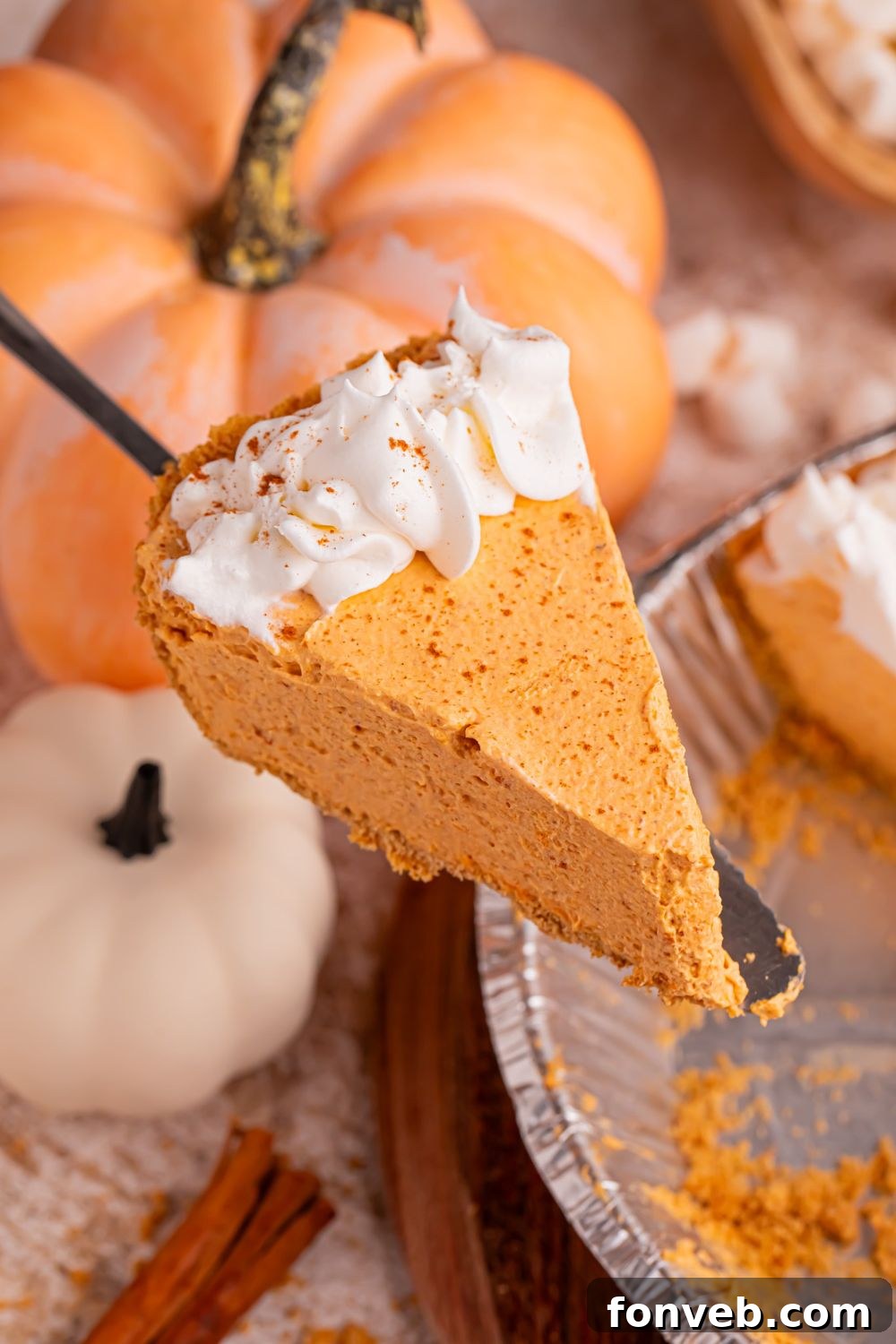 spatula with slice of pumpkin pie on it above the pie plate with the rest of the pie