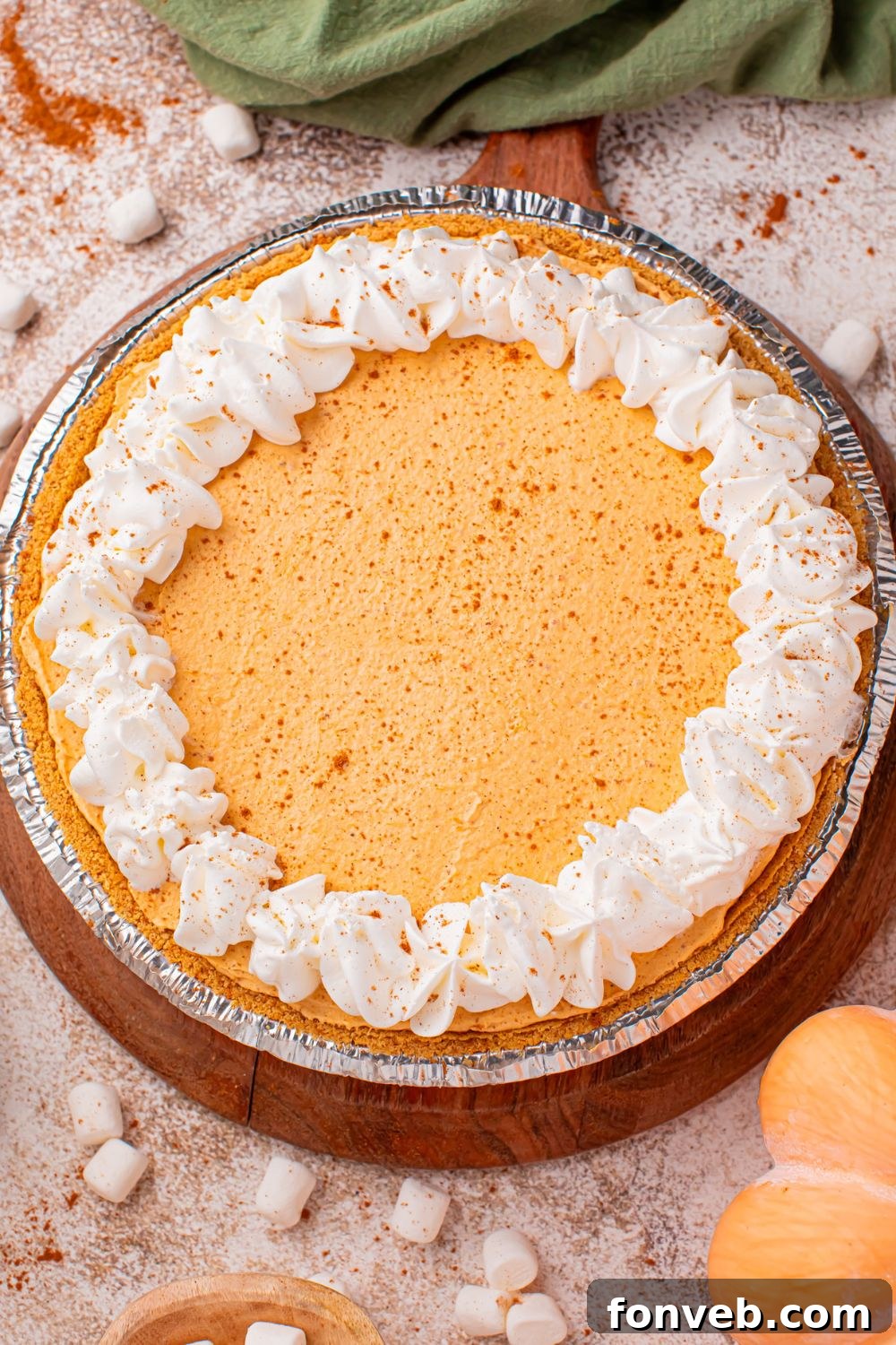 Marshmallow Pumpkin Pie on table with fall decor around it and mini marshmallows 