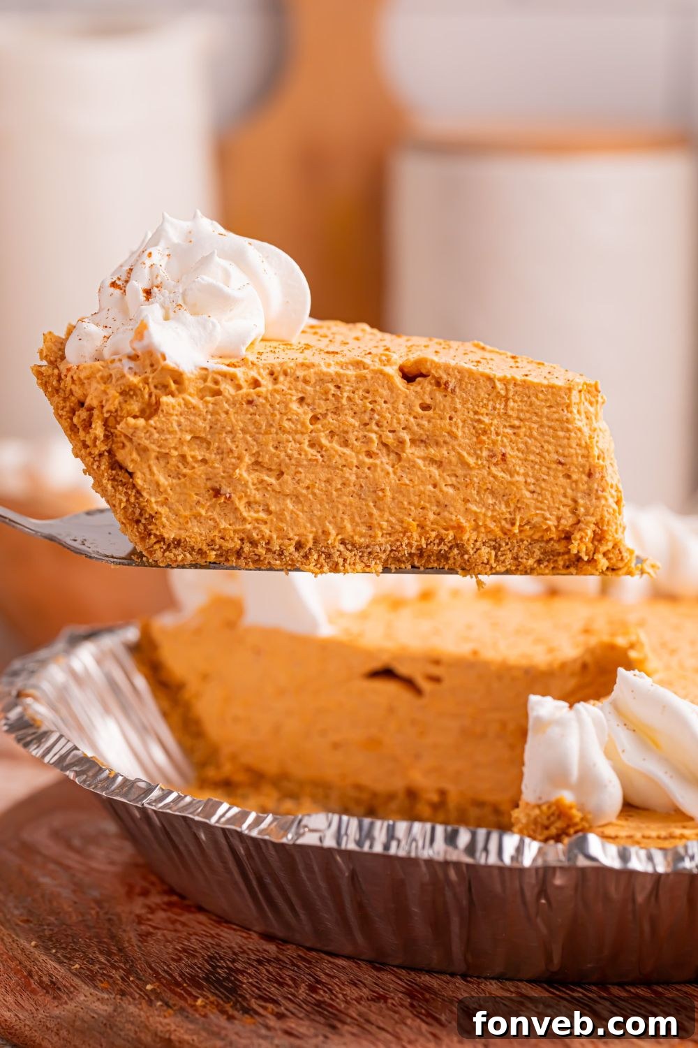 Marshmallow Pumpkin Pie on a spatula being lifted out of pie plate with the remainder of the pie 