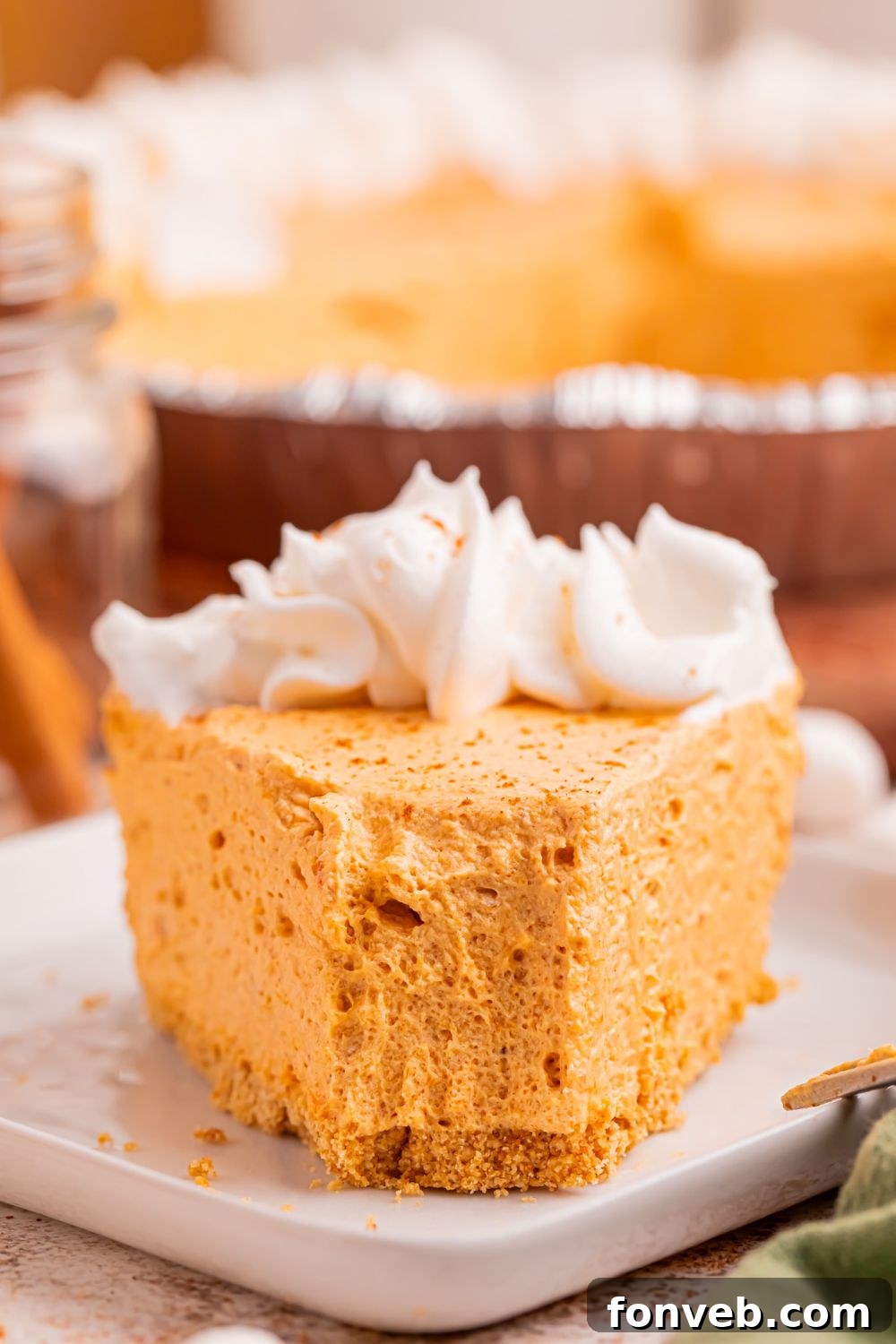 front view of a slice of marshmallow pumpkin pie on table with a fork full taken off the plate