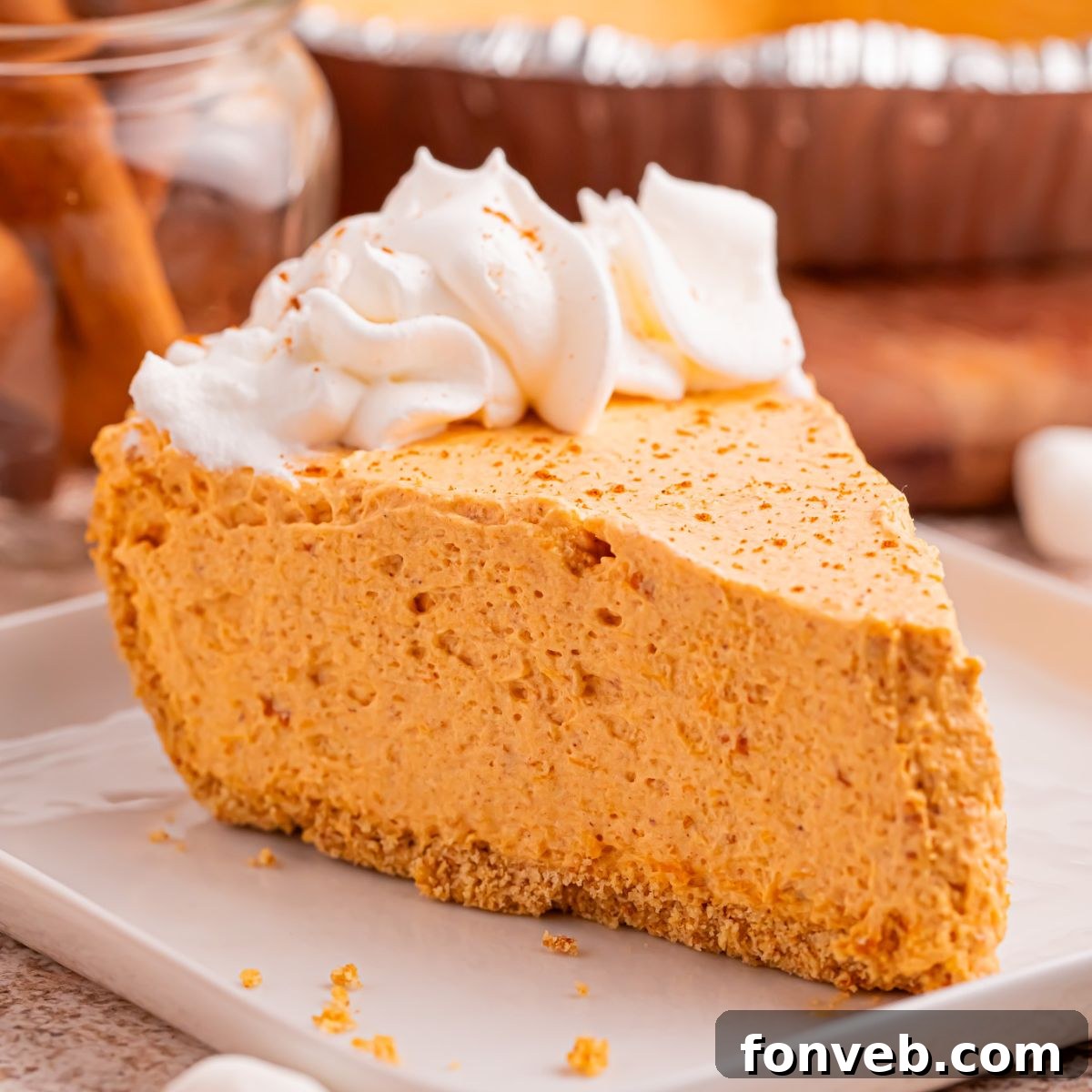Slice of Marshmallow Pumpkin Pie on plate with a few crumbs from crust sprinkled on around the table 