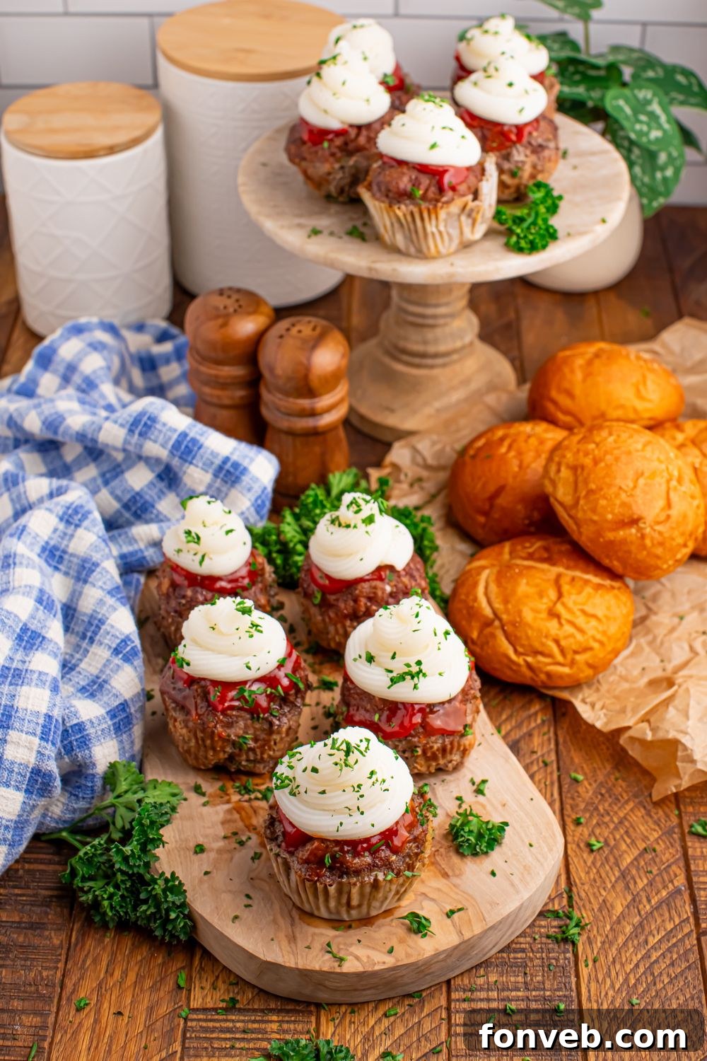 Meatloaf Cupcakes all laid out on trays on table with rolls on the side and towel and containers sitting in the background of picture 