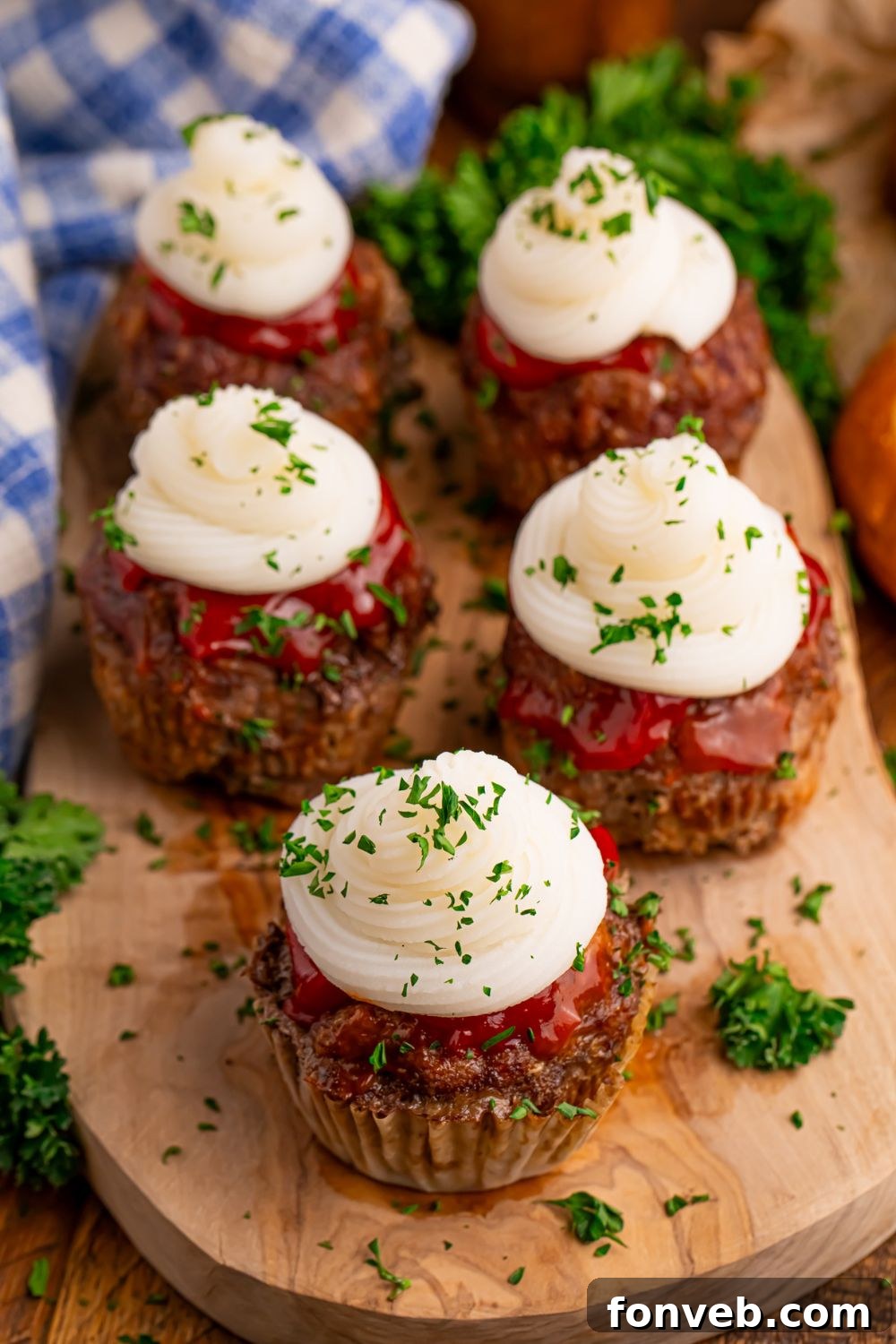 Meatloaf Cupcakes on a wooden cutting board sitting on table with a checked towel to the side and parsley sitting on side 