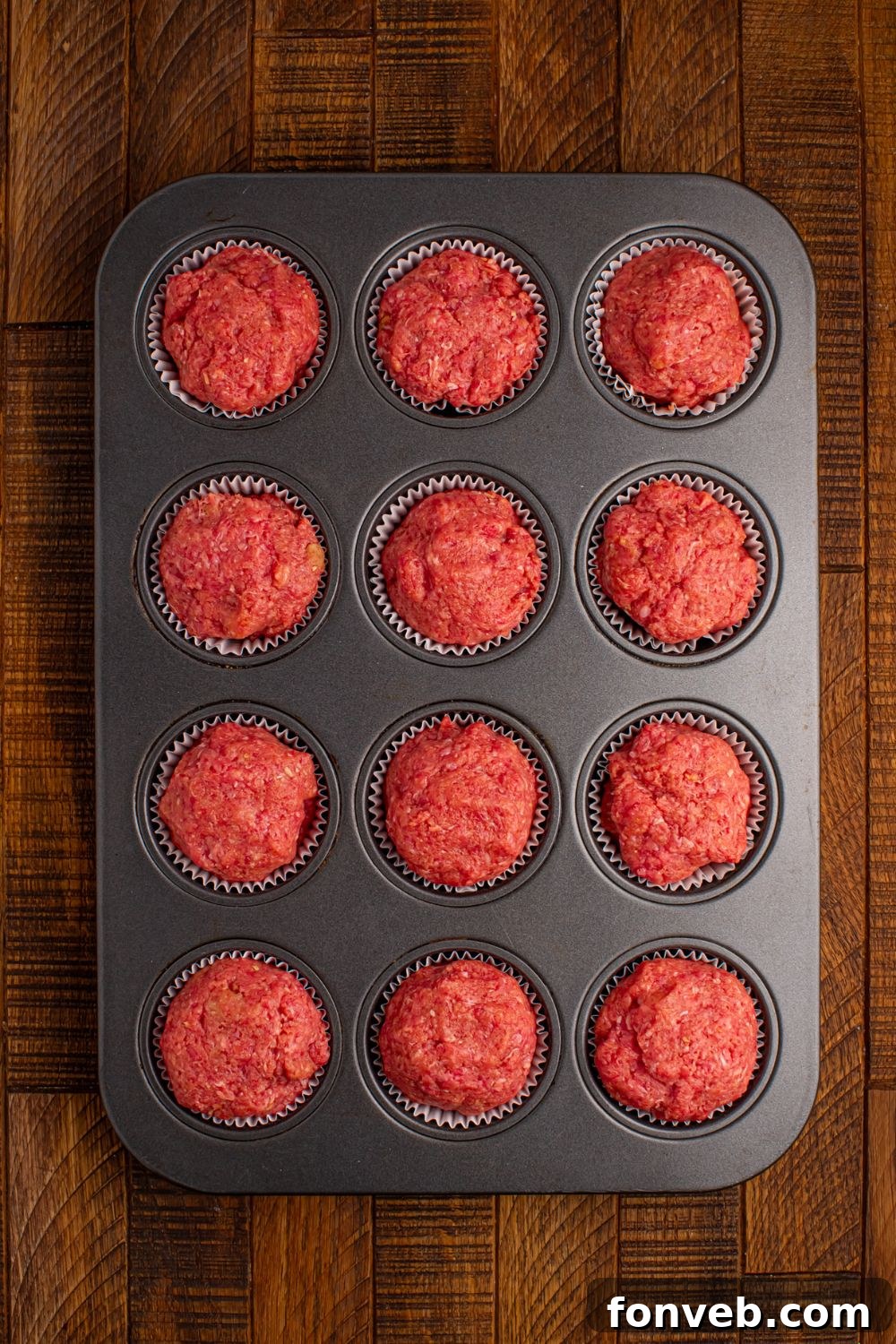 raw meatloaf in a muffin tin tray sitting on table