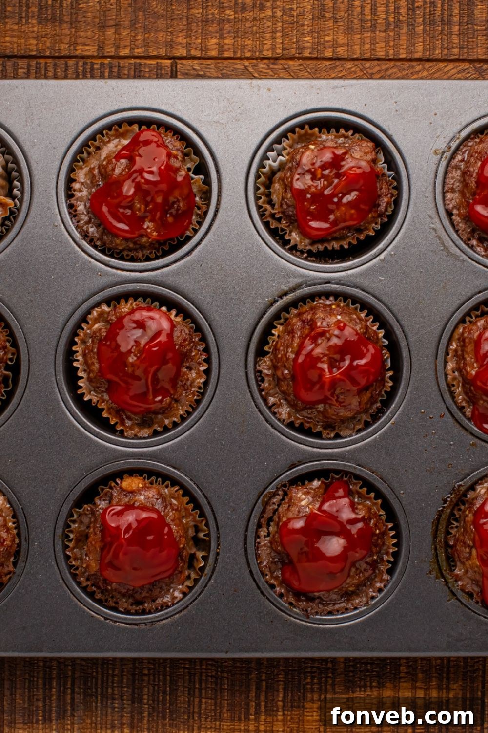 Meatloaf Cupcakes in a muffin tin with ketchup on top of each meatloaf