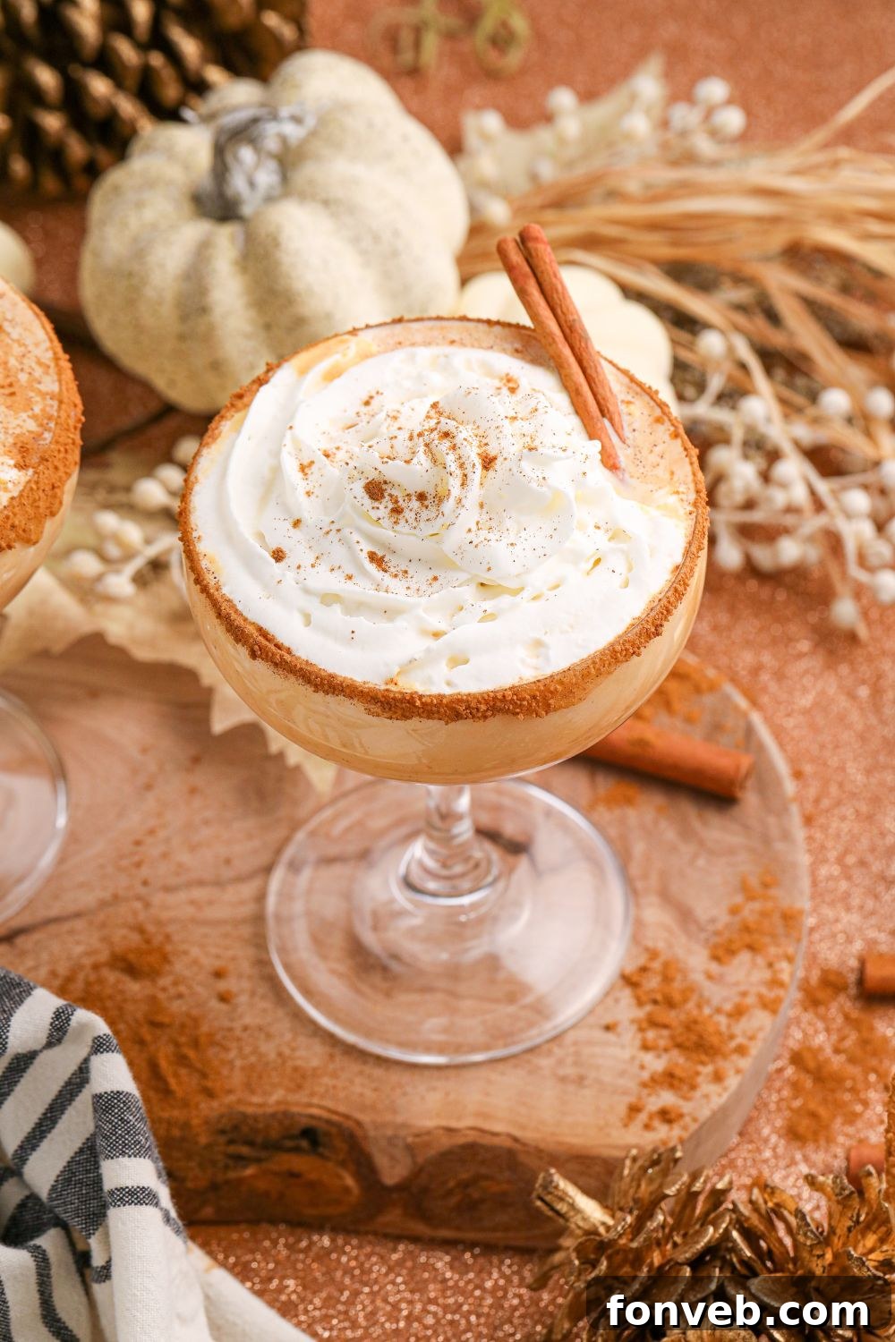 A single pumpkin martini in a glass, set on a table surrounded by autumn decorations, captures the essence of a cozy fall moment.