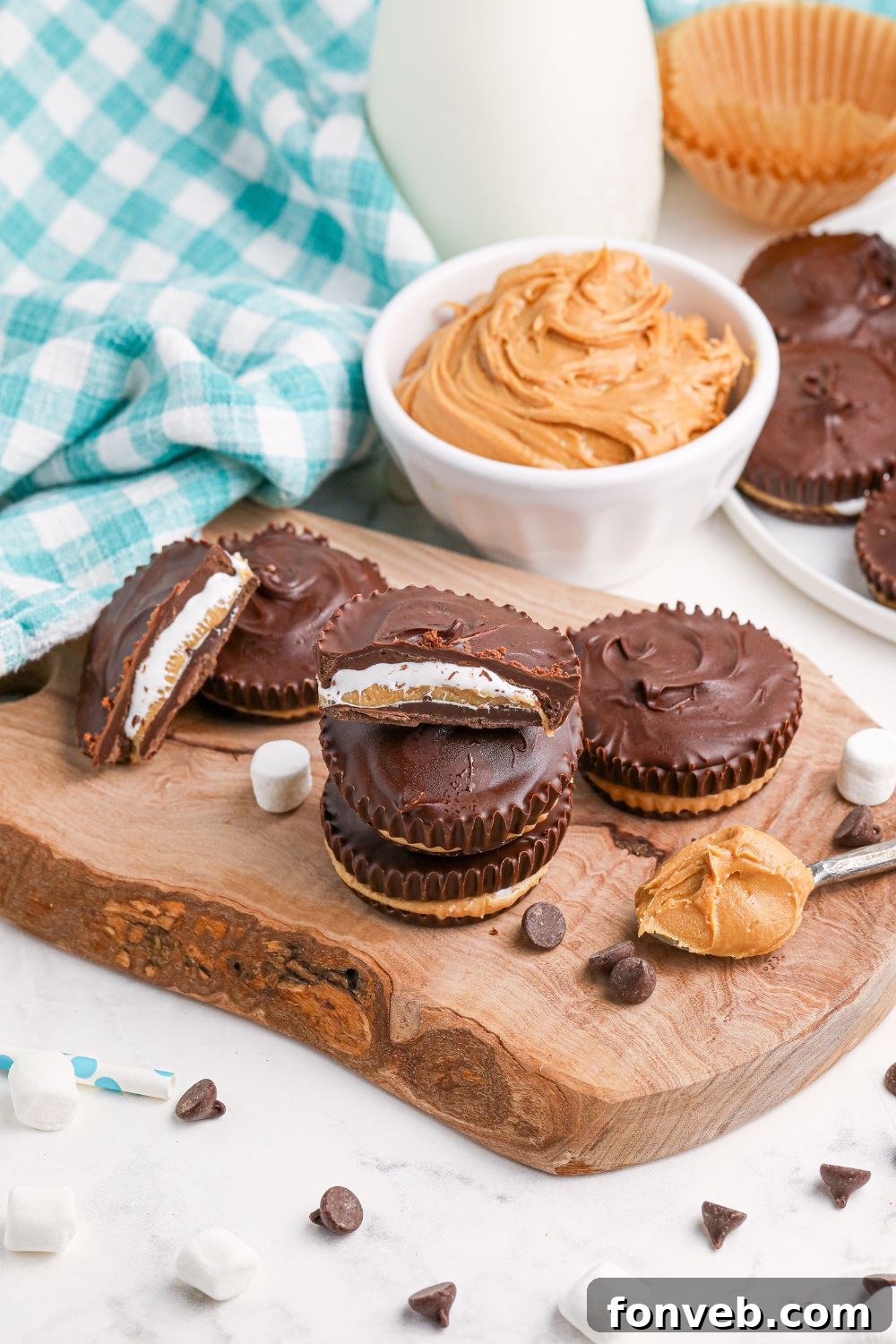 Peanut Butter Fluff Cups 13 Peanut Butter Marshmallow Cups on table with a bowl of peanut butter behind it and on a spoon next to the cups