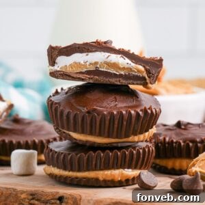 Peanut Butter Fluff Cups 18 Peanut Butter Marshmallow Cups stacked on wooden cutting board with top one cut in half so you can see the layers
