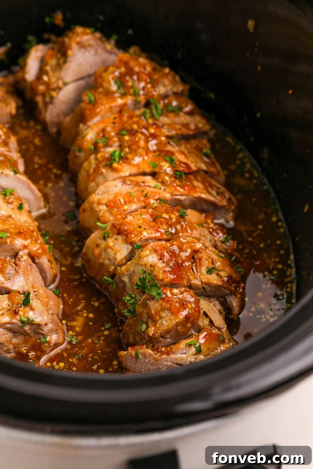 crock pot with a sliced pork tenderloin in a slow cooker 