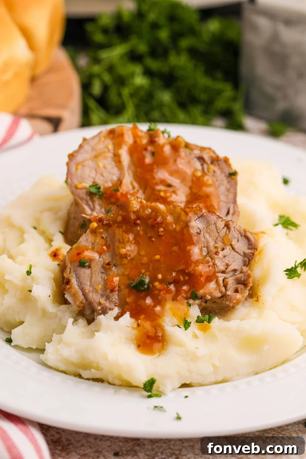 Crock Pot Apricot Pork Tenderloin on a plate with mashed potatoes under the meat 